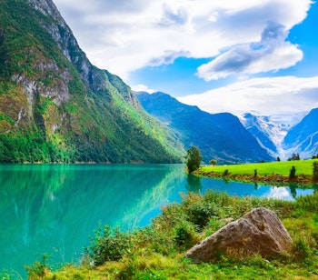 Betagende udsigt over Nordfjord med sneklædte bjerge, farverige blomster og gletsjer i Olden - idyllisk norsk naturlandskab