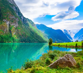 Betagende udsigt over Nordfjord med sneklædte bjerge, farverige blomster og gletsjer i Olden - idyllisk norsk naturlandskab
