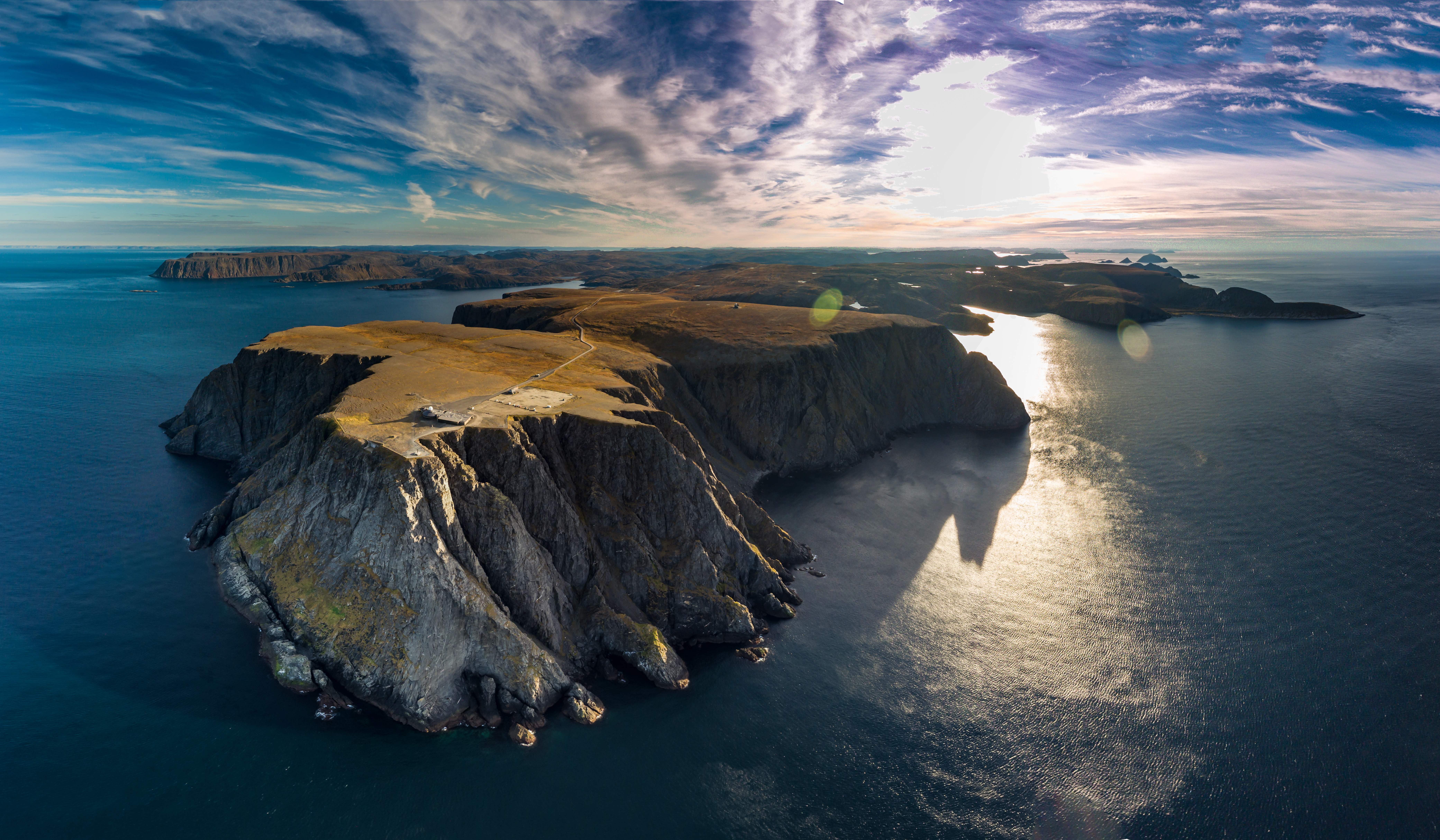 Luftfoto af Nordkap i Norge med dramatiske klipper og gyldent sollys over havet