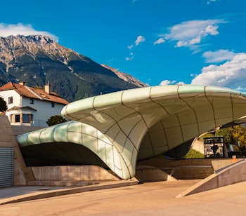 Moderne arkitektur på Nordkettenbahn stationen i Innsbruck med de imponerende Nordkette bjerge i baggrunden under en klar blå sommerhimmel i Tyrol, Østrig