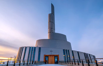 Moderne cirkulære Nordlyskatedral i sne under vinterens tusmørke i Alta Norge