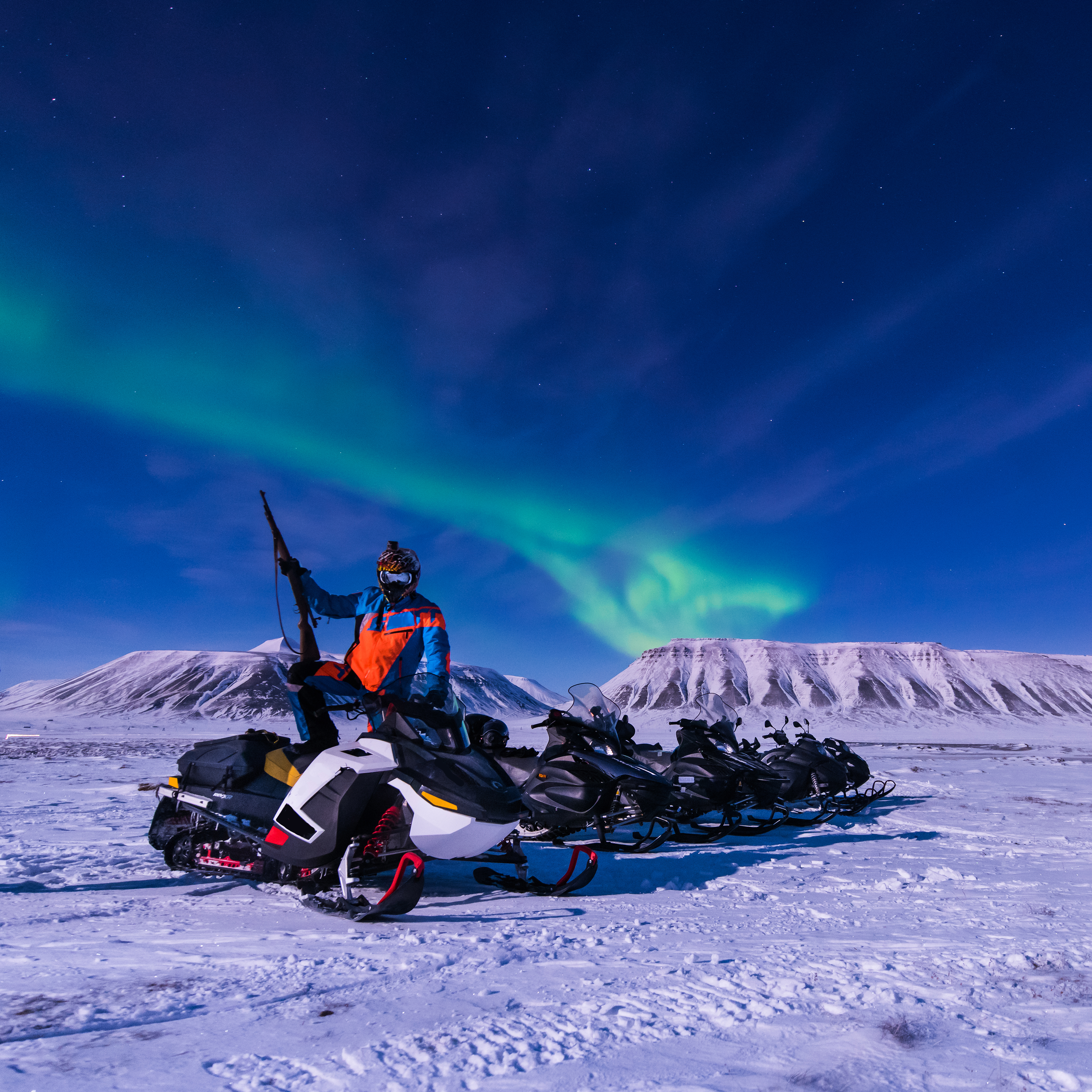Snescooterrejse under det magiske nordlys ved snedækkede bjerge i Svalbard, Longyearbyen, Norge