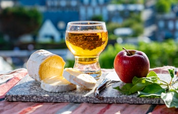 Traditionelle normanniske specialiteter med den karakteristiske Neufchâtel-ost og mousserende æblecider serveret med udsigt til de maleriske huse i Etretat-landsbyen i Normandiet