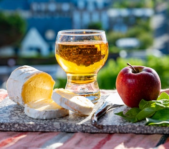 Traditionelle normanniske specialiteter med den karakteristiske Neufchâtel-ost og mousserende æblecider serveret med udsigt til de maleriske huse i Etretat-landsbyen i Normandiet