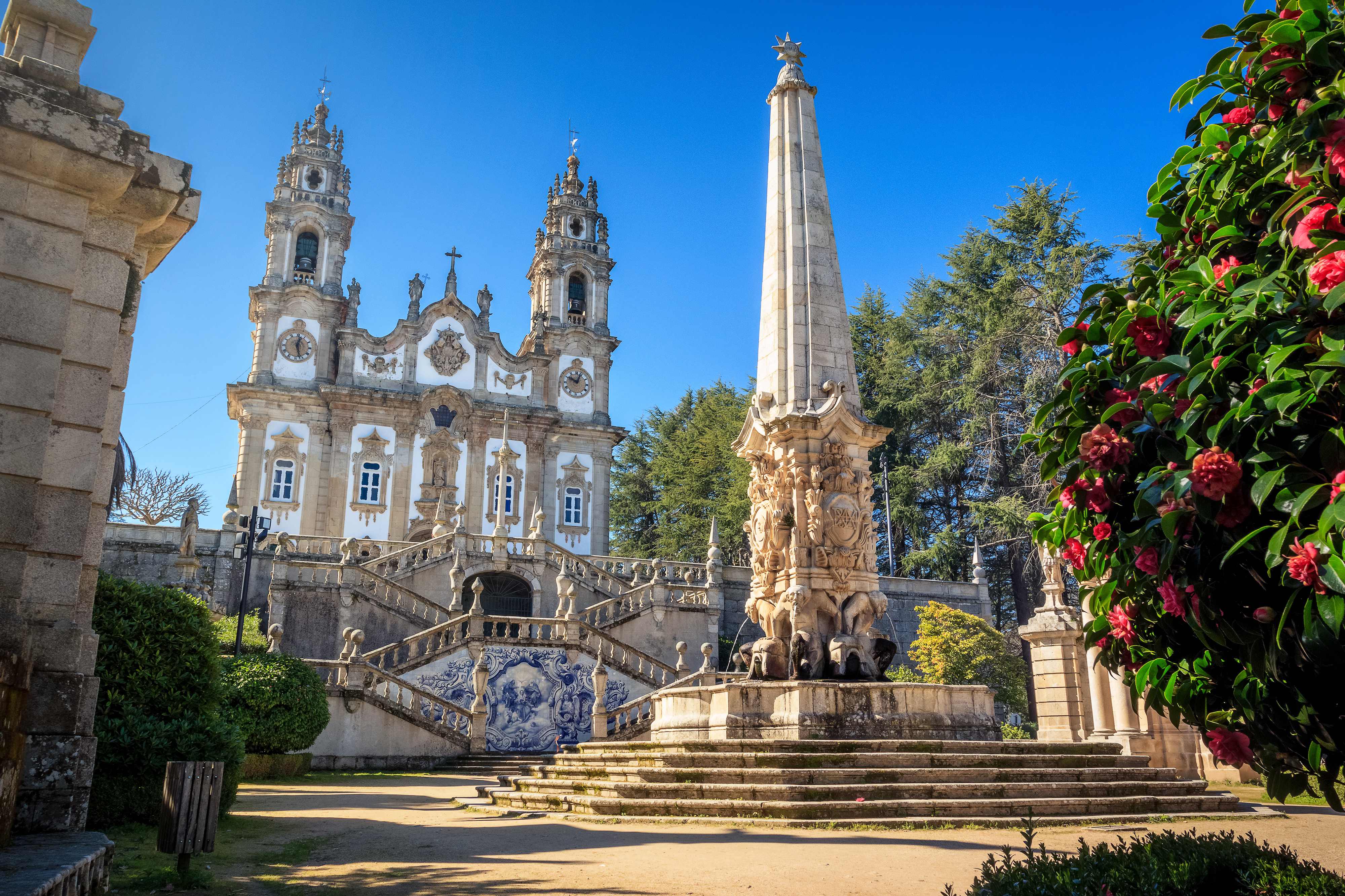Nossa Senhora dos Remédios helligdom i Lamego, Portugal, med barok kirkefacade, tvillingtårne, udsmykket obelisk-springvand og storslået trappe under blå himmel