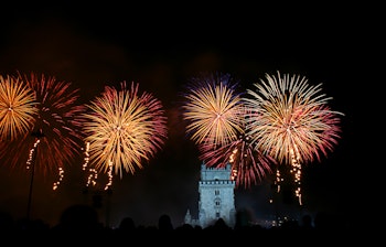 Spektakulært nytårsfyrværkeri over det historiske Belém-tårn og Tagus-floden i Lissabon, Portugal, som skaber en festlig stemning under nytårsfejringen