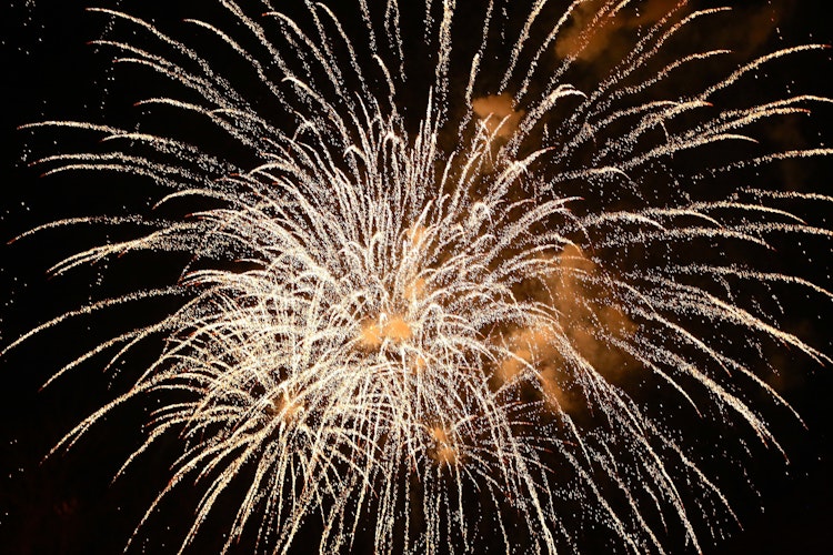 Festligt nytårsfyrværkeri over vandet i Lissabon, Portugal med farverige eksplosioner der spejler sig i vandoverfladen