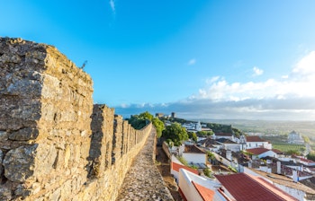 Historiske fæstningsmure fra det 11. århundrede med udsigt over de farverige huse med røde tegltage i middelalderbyen Óbidos, Portugal