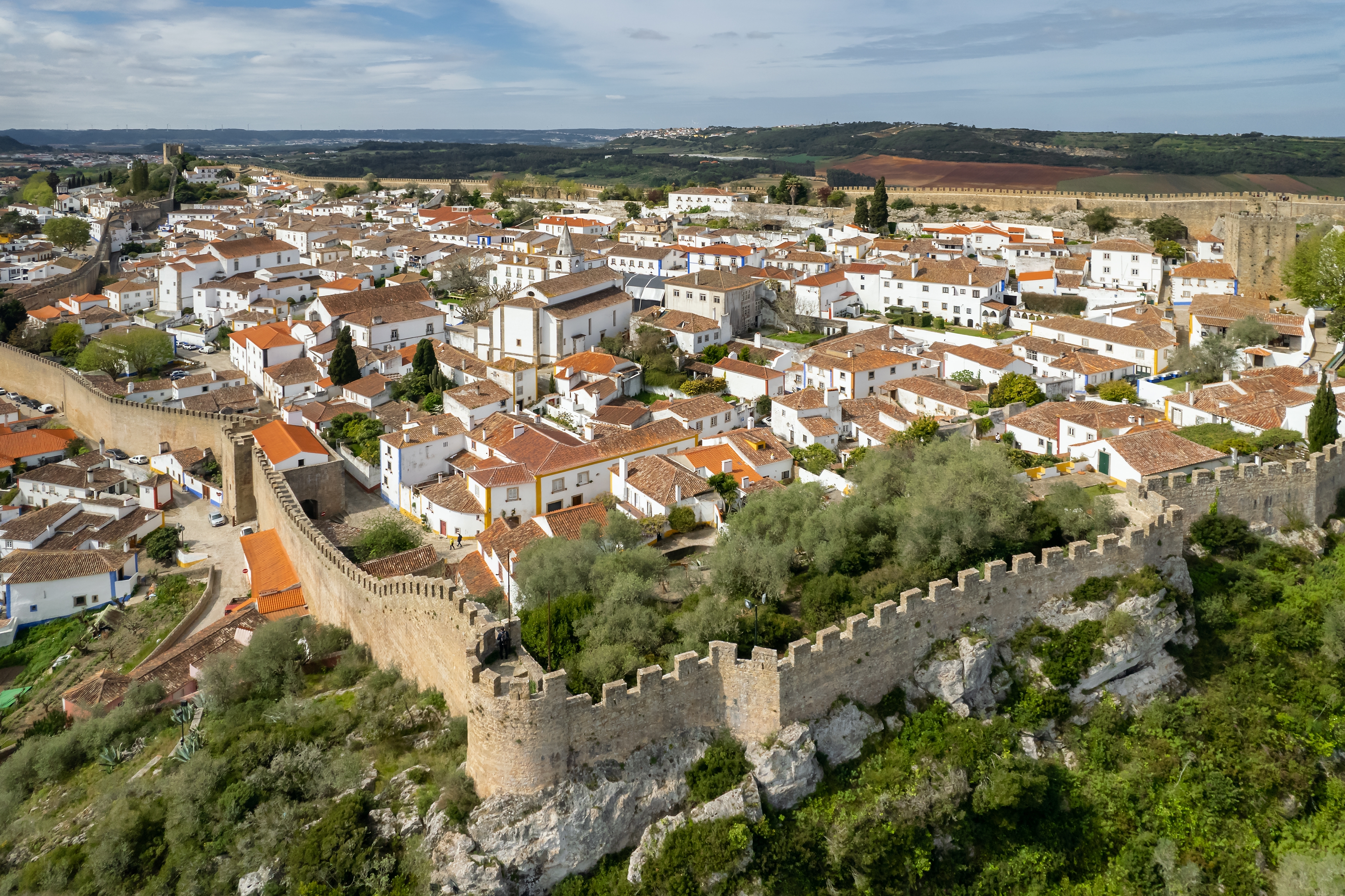 Luftfoto over den middelalderlige befæstede by Óbidos i Portugal med hvide huse, orangefarvede tagsten og gamle bymure