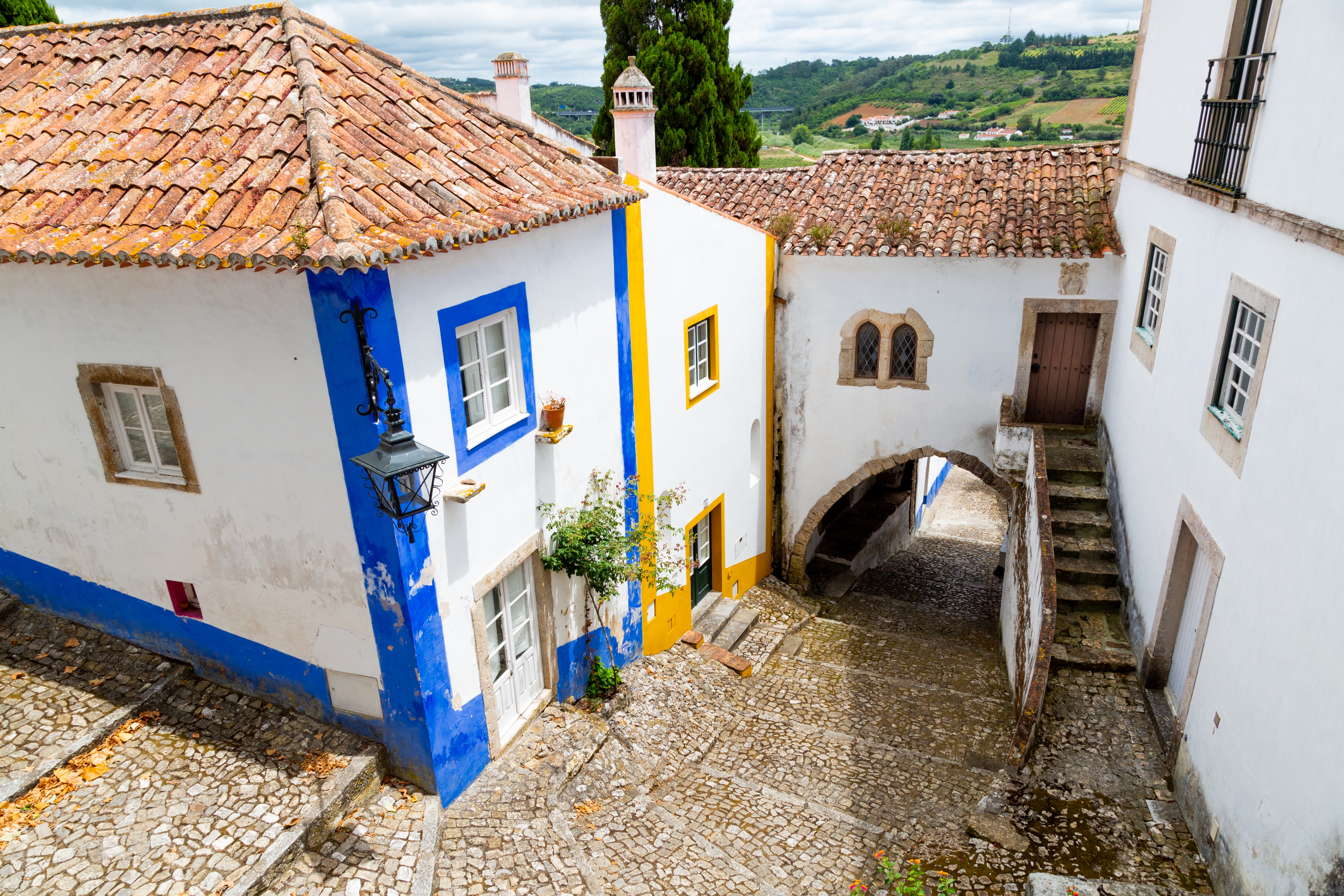 Pittoresk middelalderby Obidos i Portugal med hvide huse, blå og gule detaljer og røde tegltagsstene