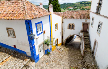 Pittoresk middelalderby Obidos i Portugal med hvide huse, blå og gule detaljer og røde tegltagsstene
