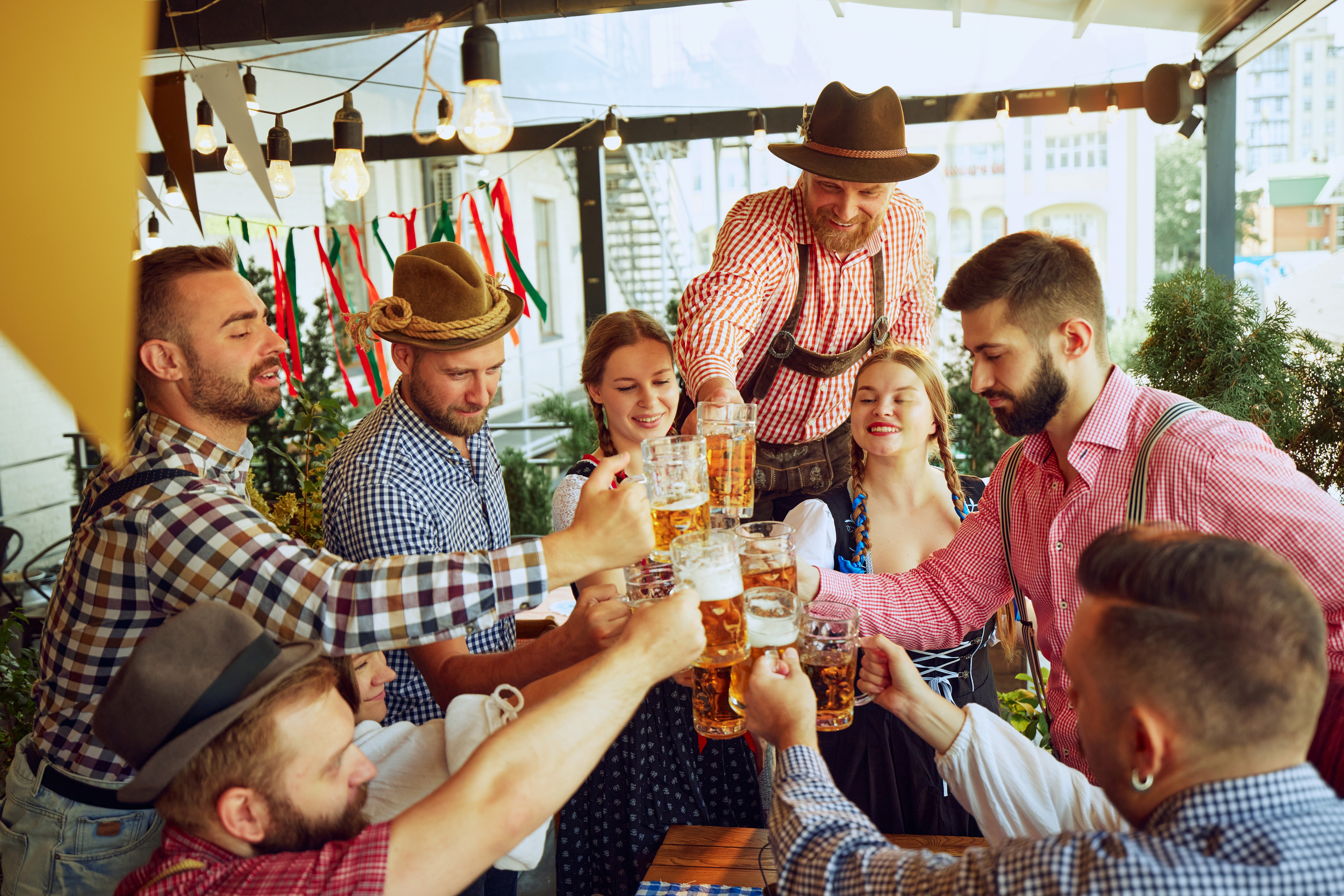 Vennegruppe i traditionelt bayersk tøj skåler med ølkrus under Oktoberfest i München