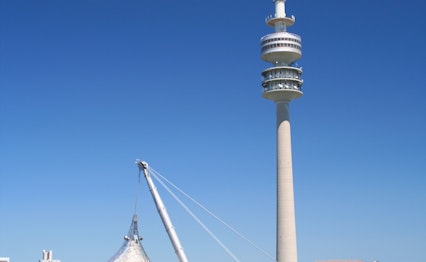 Olympiaparken i München med det ikoniske olympiatårn og stadion under klar blå himmel i Bayern, Tyskland