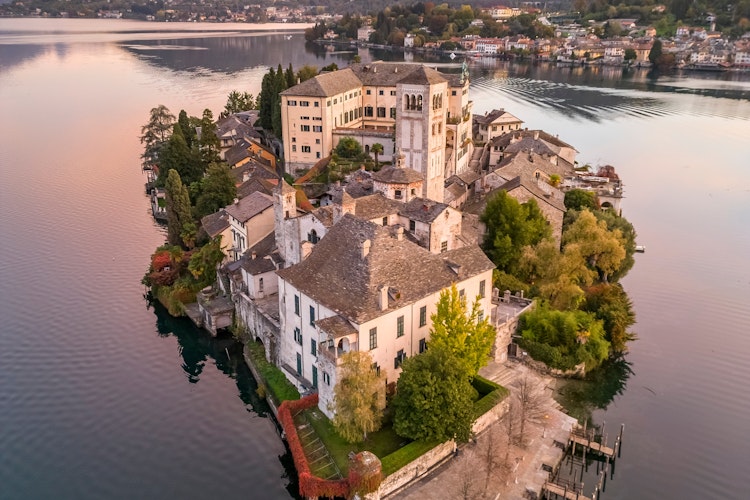 San Giulio-øen ved solopgang på den smukke Orta-sø med efterårsfarver i Piemonte, Norditalien