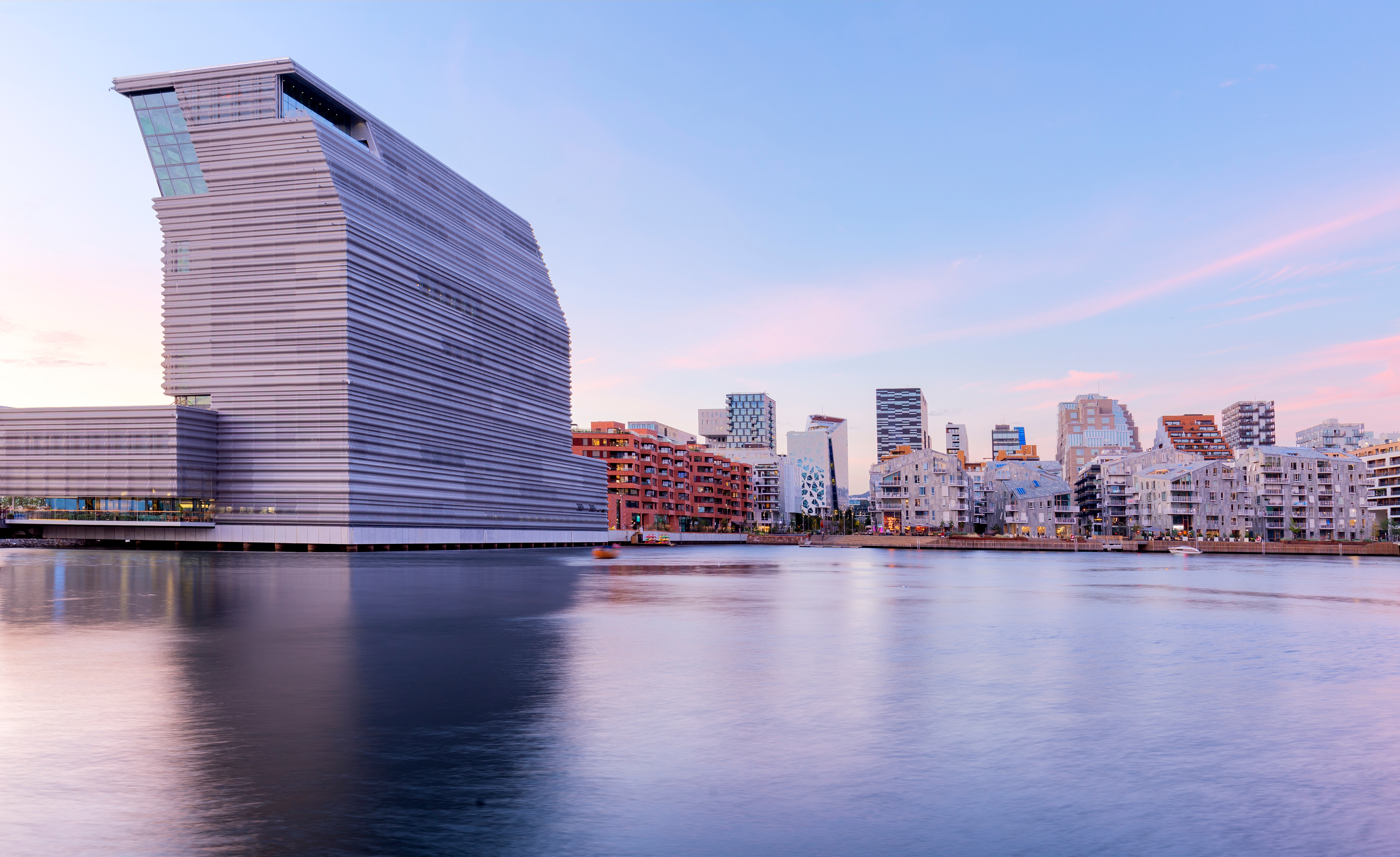 Oslo skyline med moderne glasbyggeri og refleksioner i fjorden ved solnedgang