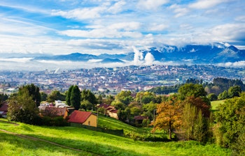 Panoramaudsigt over Oviedo by med Santa Maria del Naranco kirke og asturianske bjerge i Nordspanien