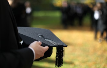 Kandidat holder sort morterbrætshue under dimissionsceremoni på Oxford Universitet i efteråret