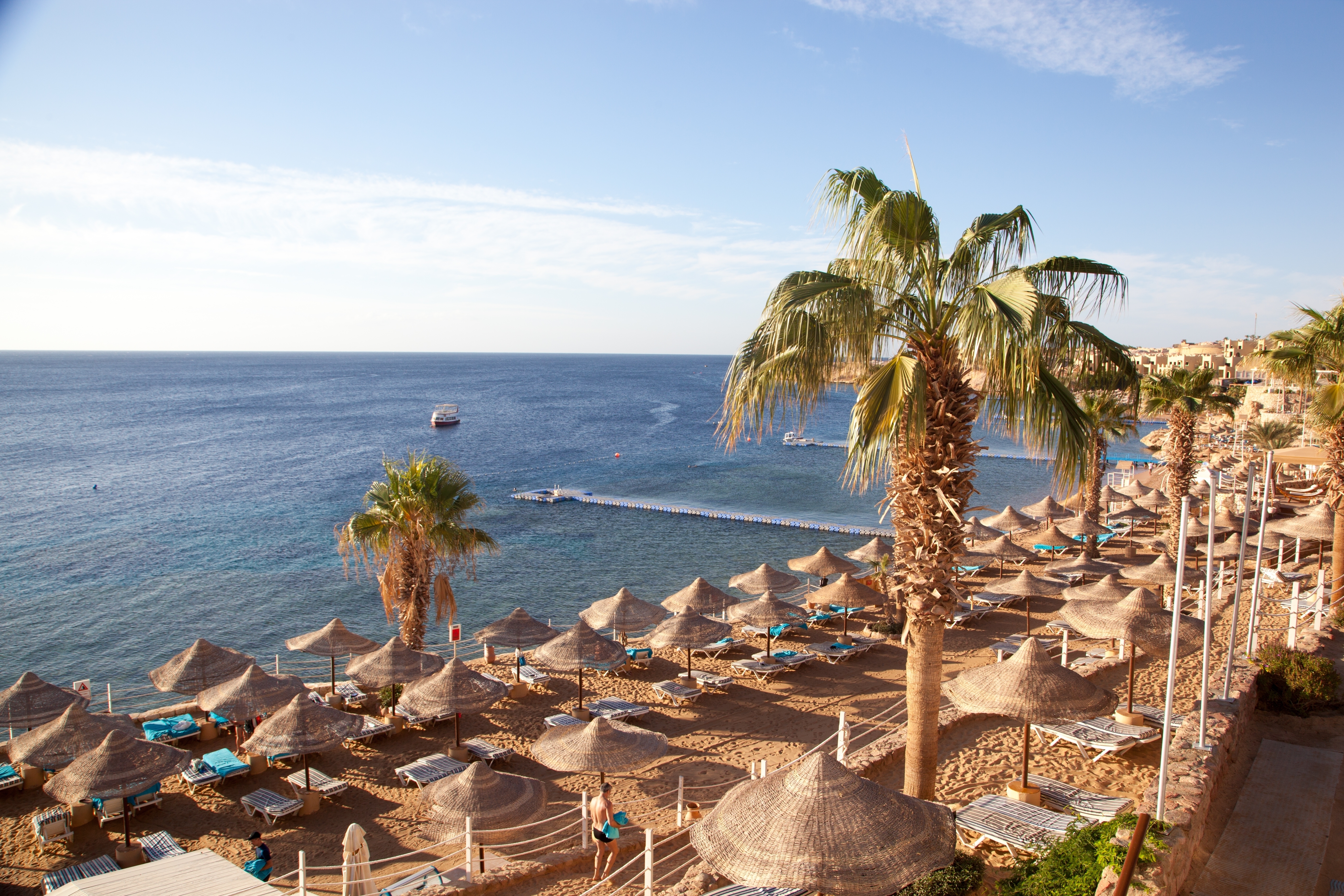 Idyllisk strandresort med palmer og stråparasoller ved Det Røde Havs krystalklare vand i Aqaba, Jordan