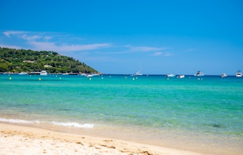 Idyllisk hvid sandstrand ved Pampelonne nær Saint-Tropez med krystalklart turkisblåt vand, perfekt til en luksuriøs sommerferie på den franske riviera