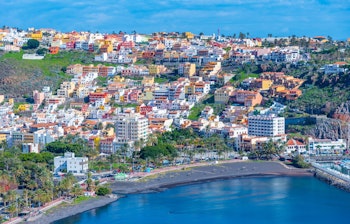 Panoramaudsigt over San Sebastian på La Gomera med farverig arkitektur, historisk bymidte og naturskøn havn omgivet af bjerge