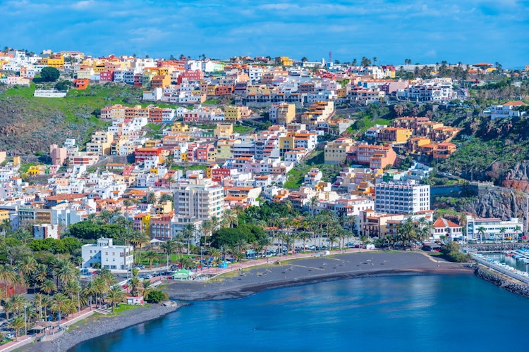 Panoramaudsigt over San Sebastian på La Gomera med farverig arkitektur, historisk bymidte og naturskøn havn omgivet af bjerge