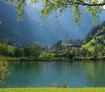 Idyllisk panoramaudsigt over den alpine landsby Selva di Molini i Sydtyrol med bjerglandskab, sø og traditionel arkitektur
