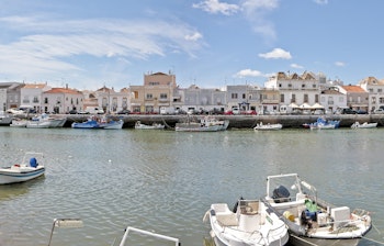 Betagende panoramaudsigt over den historiske by Tavira i Algarve, Portugal, med traditionelle bygninger langs floden og farverige både