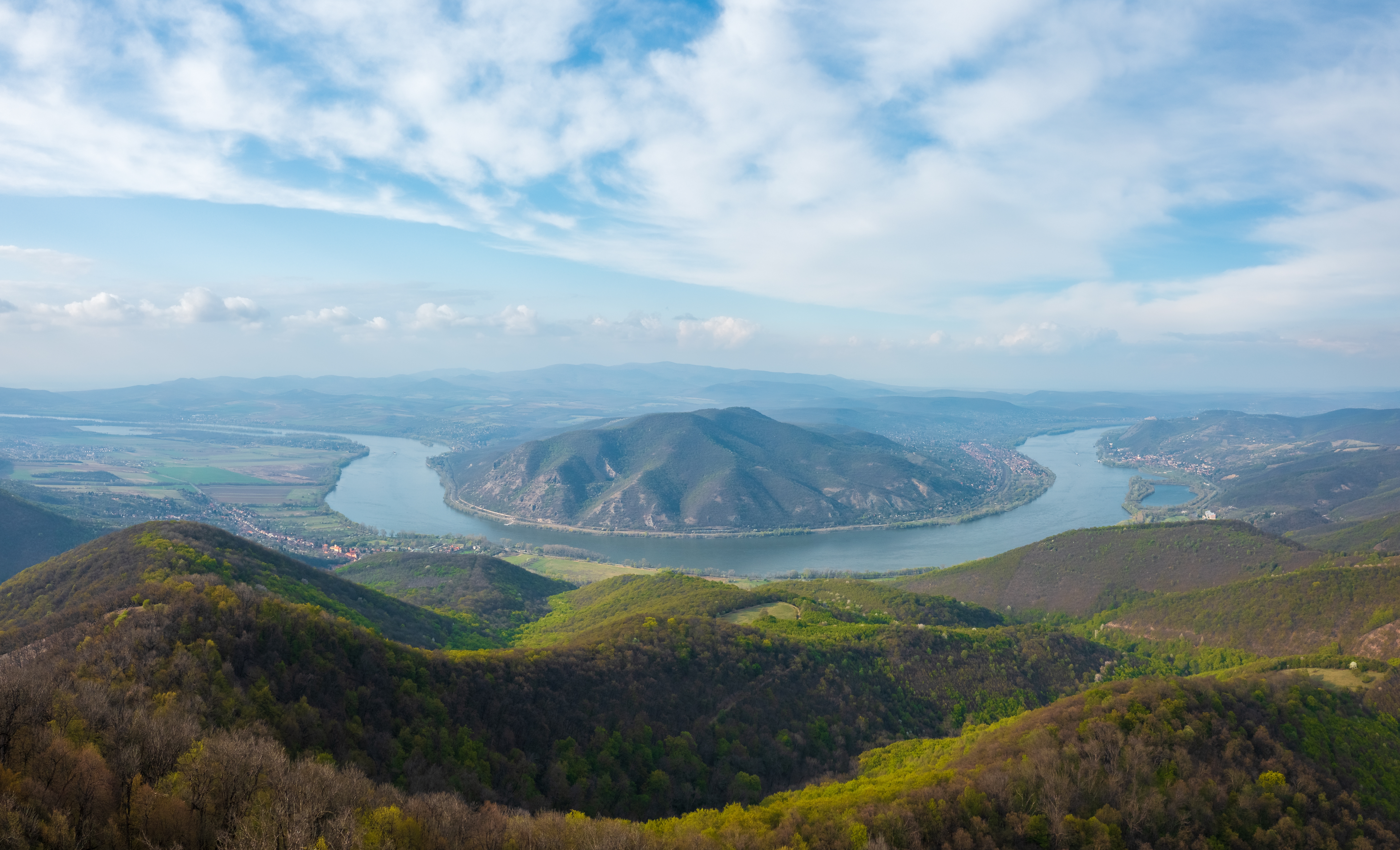 Betagende panoramaudsigt over Donauslyngningen fra Prédikálószék udsigtspunkt med Dömös og Visegrád i baggrunden, omgivet af forårsgrønne bjerge og skove