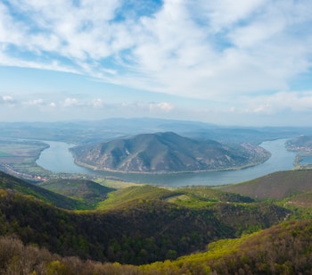 Betagende panoramaudsigt over Donauslyngningen fra Prédikálószék udsigtspunkt med Dömös og Visegrád i baggrunden, omgivet af forårsgrønne bjerge og skove