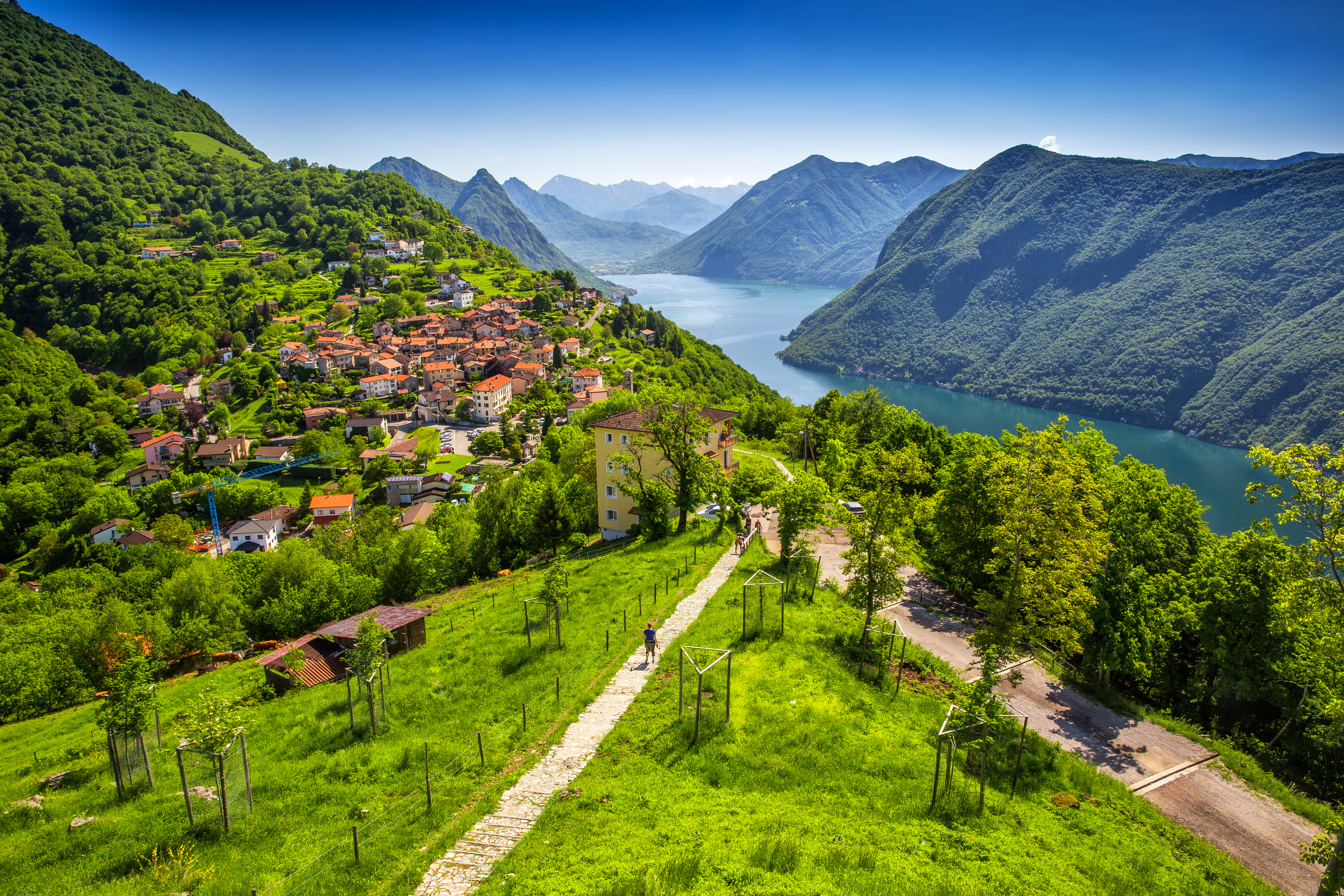 Betagende panoramaudsigt over Lugano by og sø set fra Monte Bre med blomstrende haver og Monte San Salvatore i baggrunden, Ticino, Schweiz
