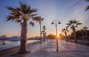 Historisk fort i Paphos oplyst ved solnedgang med smukke reflektioner i havnens vand, Cypern