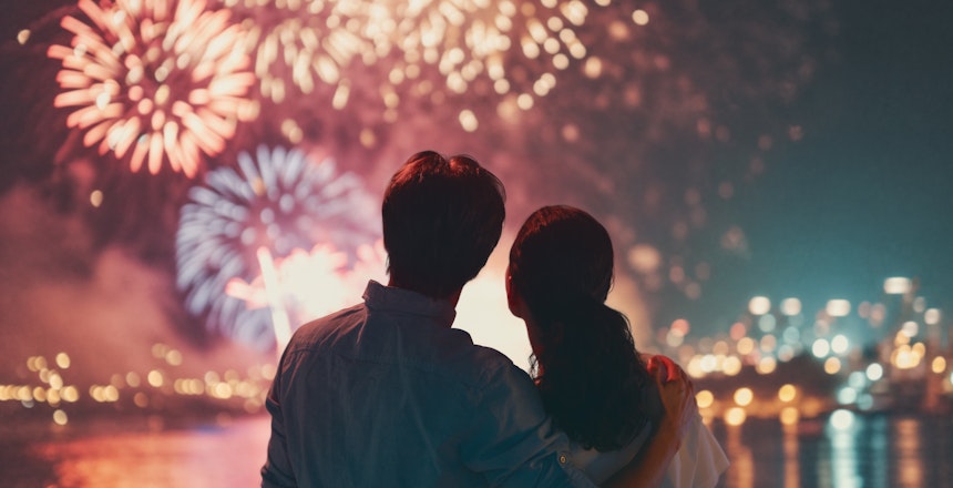 Romantisk par der sammen nyder det farverige nytårsfyrværkeri på deres nytårsrejse
