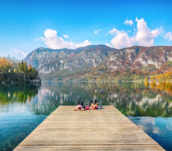 Par nyder udsigten over Bohinj-søen fra træbro med smukke bjerge i baggrunden, Triglav Nationalpark i Slovenien