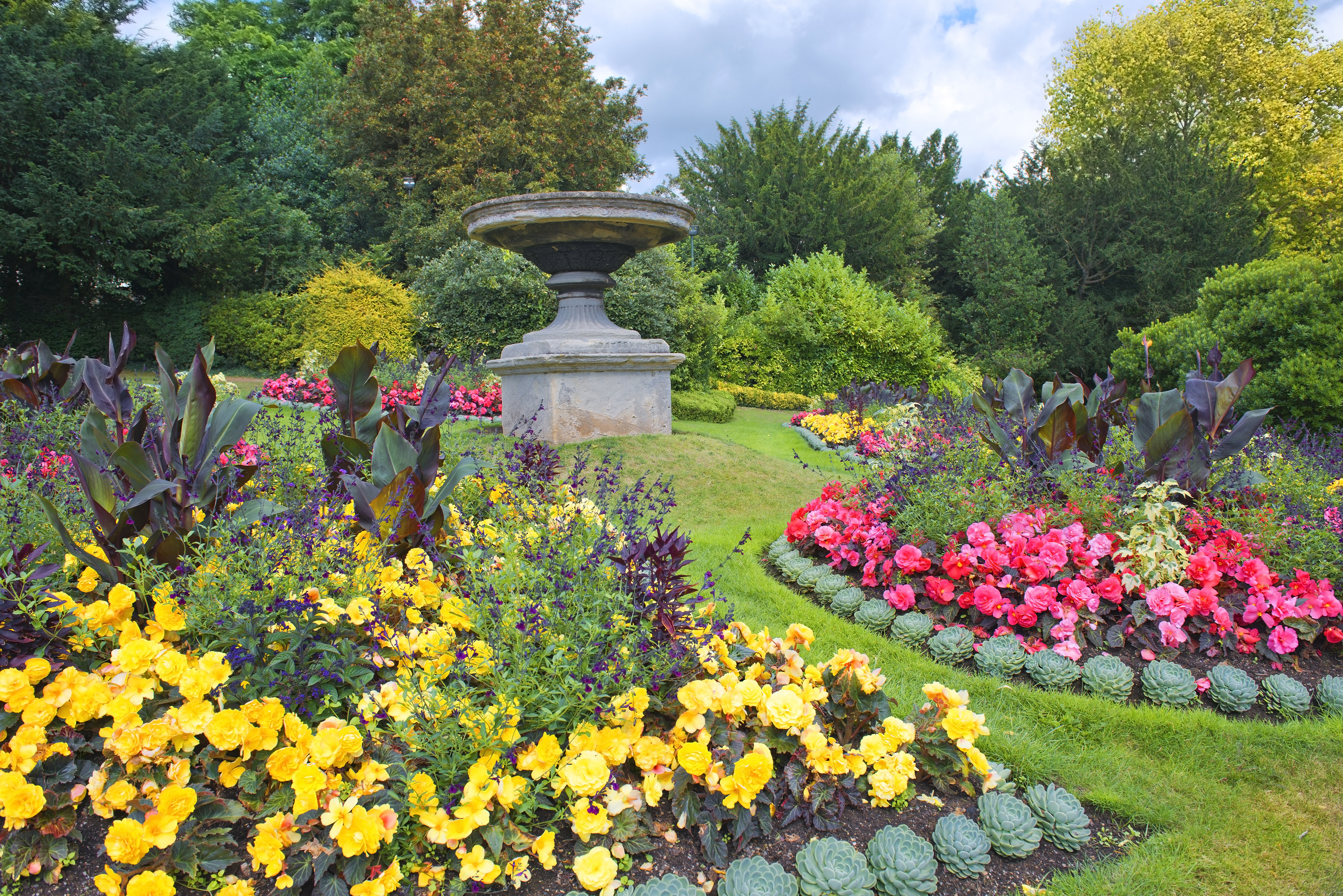 Farverige blomsterbede i Parade Gardens, Bath - en historisk engelsk have med veltrimmede plæner og stenskulptur