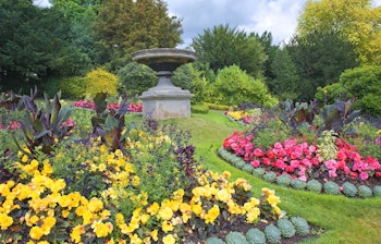 Farverige blomsterbede i Parade Gardens, Bath - en historisk engelsk have med veltrimmede plæner og stenskulptur