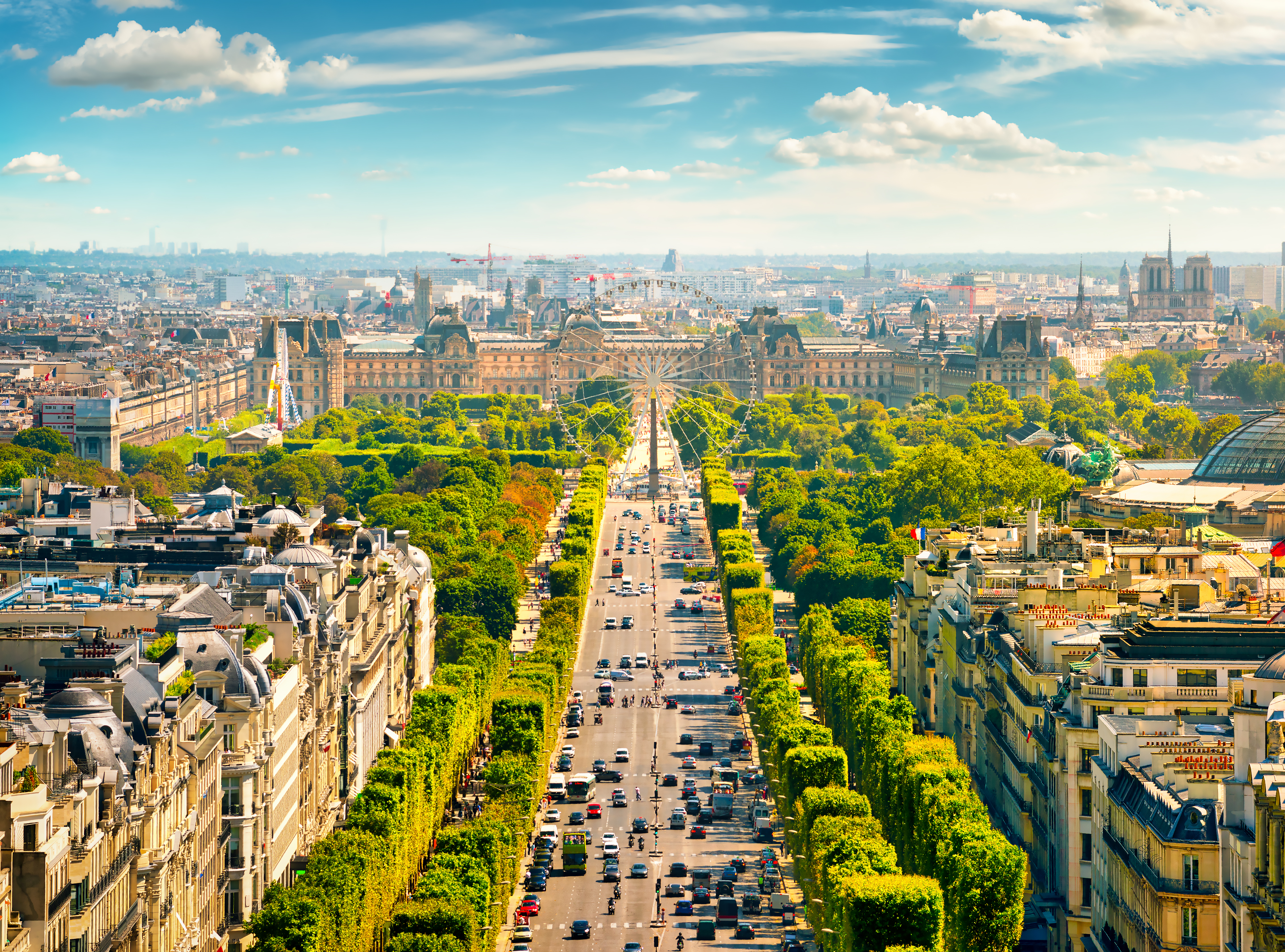 Luftudsigt over Avenue des Champs-Élysées fra Arc de Triomphe i Paris med træbeklædt boulevard og byens skyline