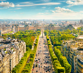 Luftudsigt over Avenue des Champs-Élysées fra Arc de Triomphe i Paris med træbeklædt boulevard og byens skyline