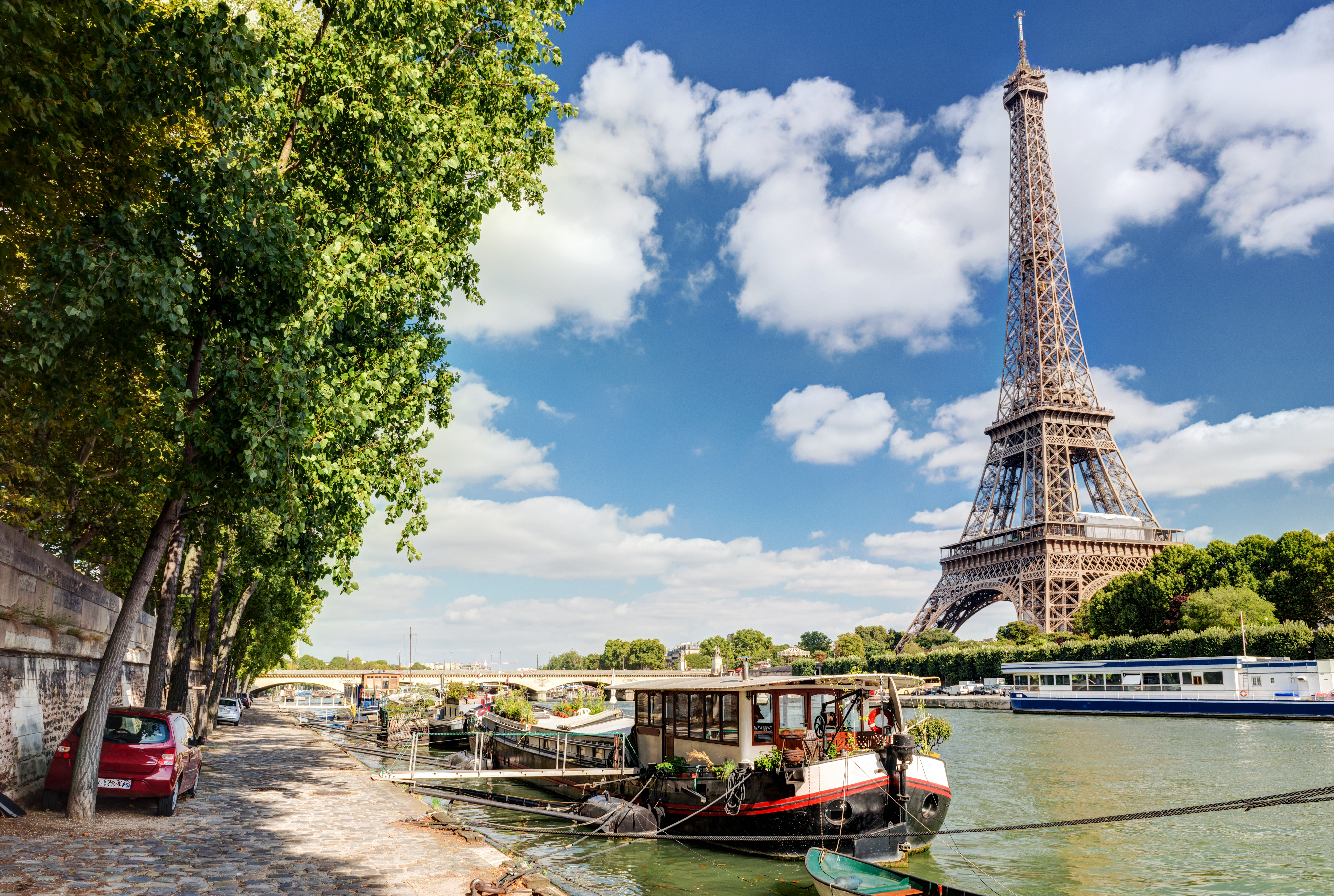 Idyllisk udsigt over Paris med Eiffeltårnet og husbåde på Seinen på en solrig sommerdag