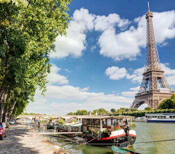 Idyllisk udsigt over Paris med Eiffeltårnet og husbåde på Seinen på en solrig sommerdag