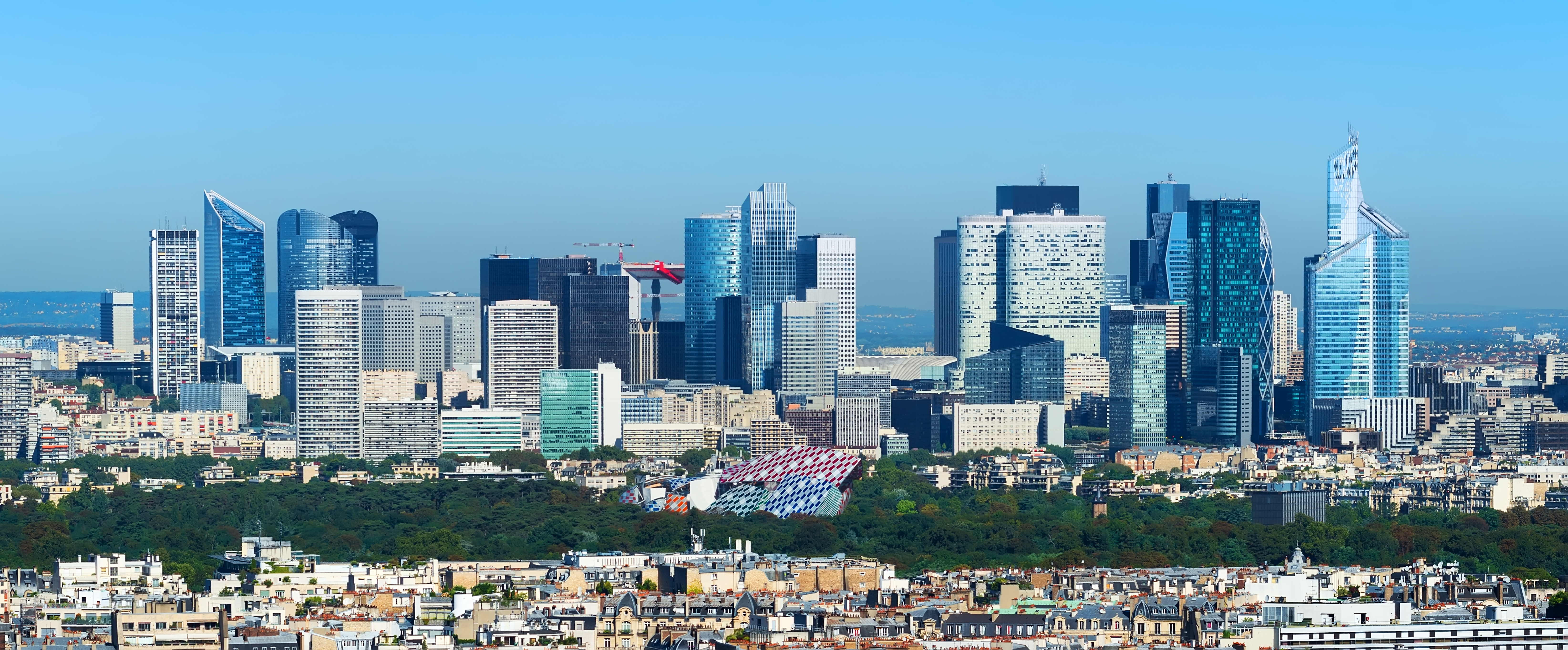 Panoramisk udsigt over La Defense forretningskvarter i Paris med moderne skyskrabere under blå himmel