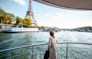 Ung kvinde nyder solnedgangen under baadtur paa Seinen med udsigt til Eiffeltaarnet i Paris
