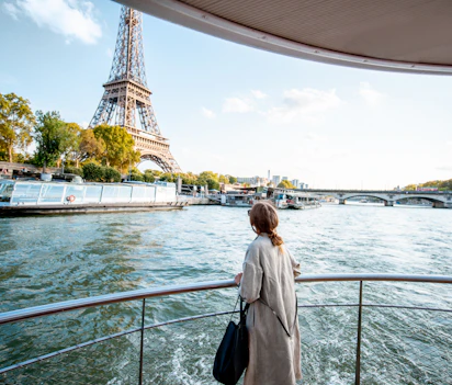Ung kvinde nyder solnedgangen under baadtur paa Seinen med udsigt til Eiffeltaarnet i Paris