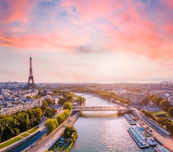 Betagende luftpanorama over Paris med Seinen og Eiffeltårnet badet i solnedgangens gyldne lys - den perfekte destination for en romantisk storbyferie i Frankrig