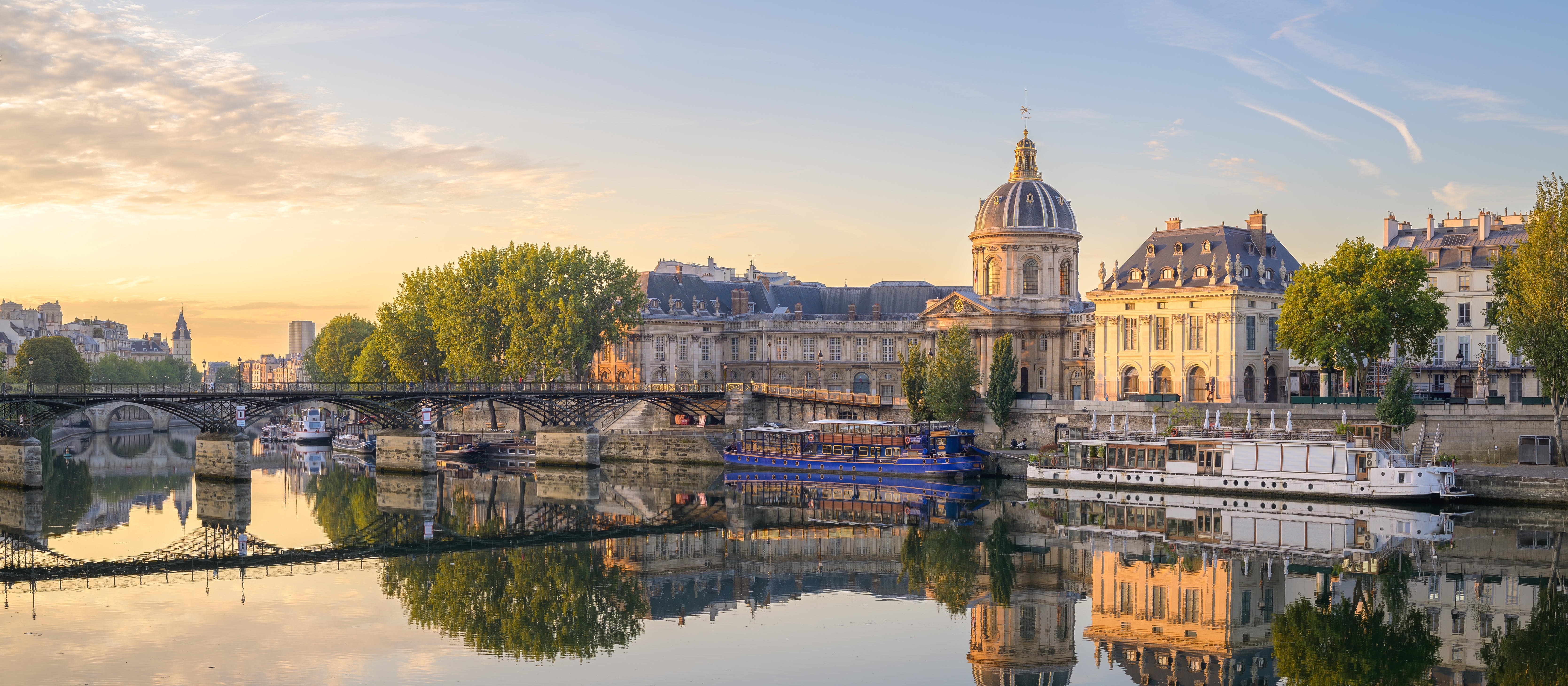 Smuk solopgang over Seinen i Paris med Pont des Arts broen og Institut de France spejlet i det rolige vand