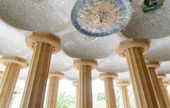 Farverig mosaikdekoreret loft i søjlehallen Sala Hipostila i Park Güell, Barcelona, med Antoni Gaudís karakteristiske arkitektur og stensøjler