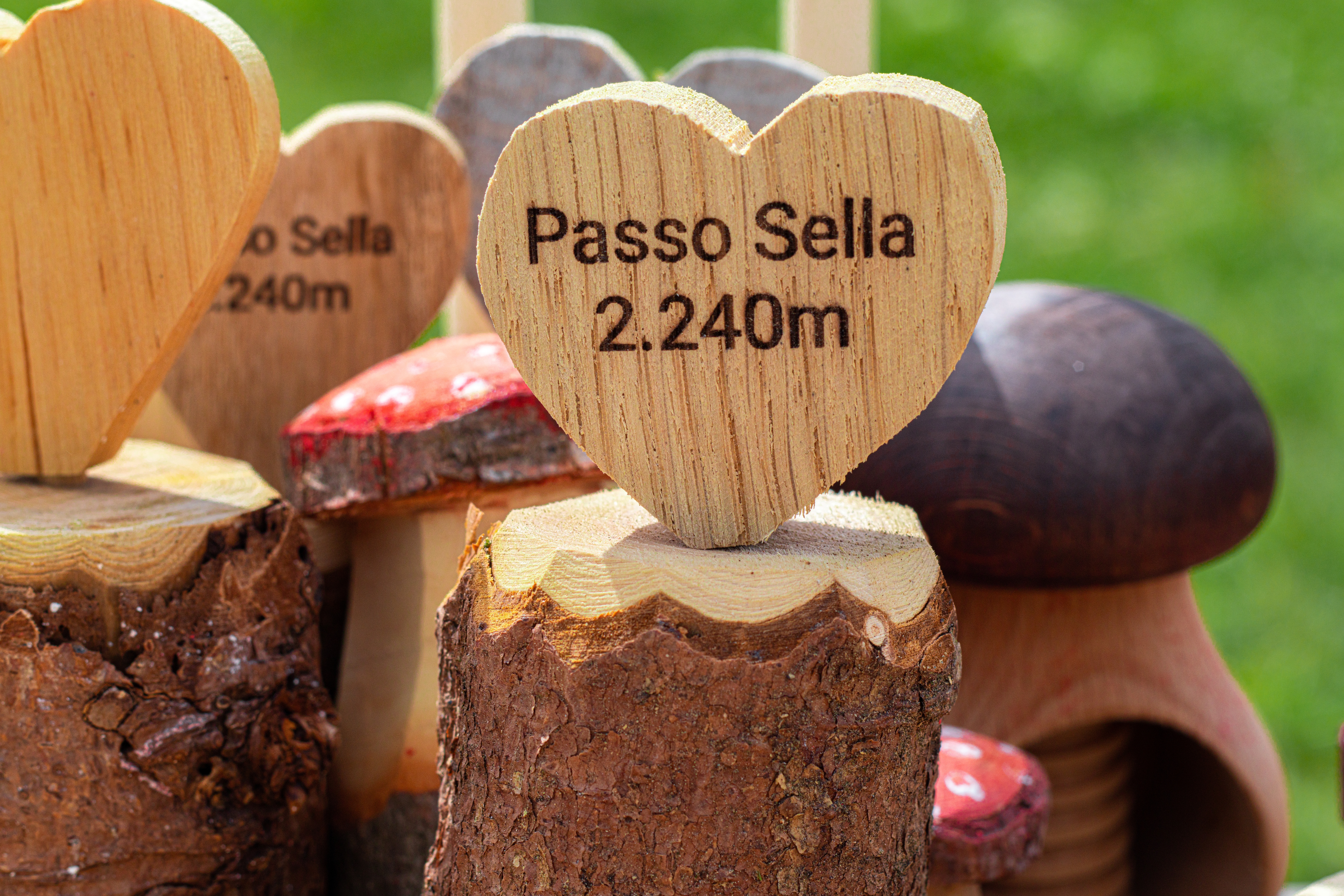 Håndlavet træhjerte souvenir med graveret tekst Passo Sella 2240m på rustik træstub i Dolomitterne, Italien