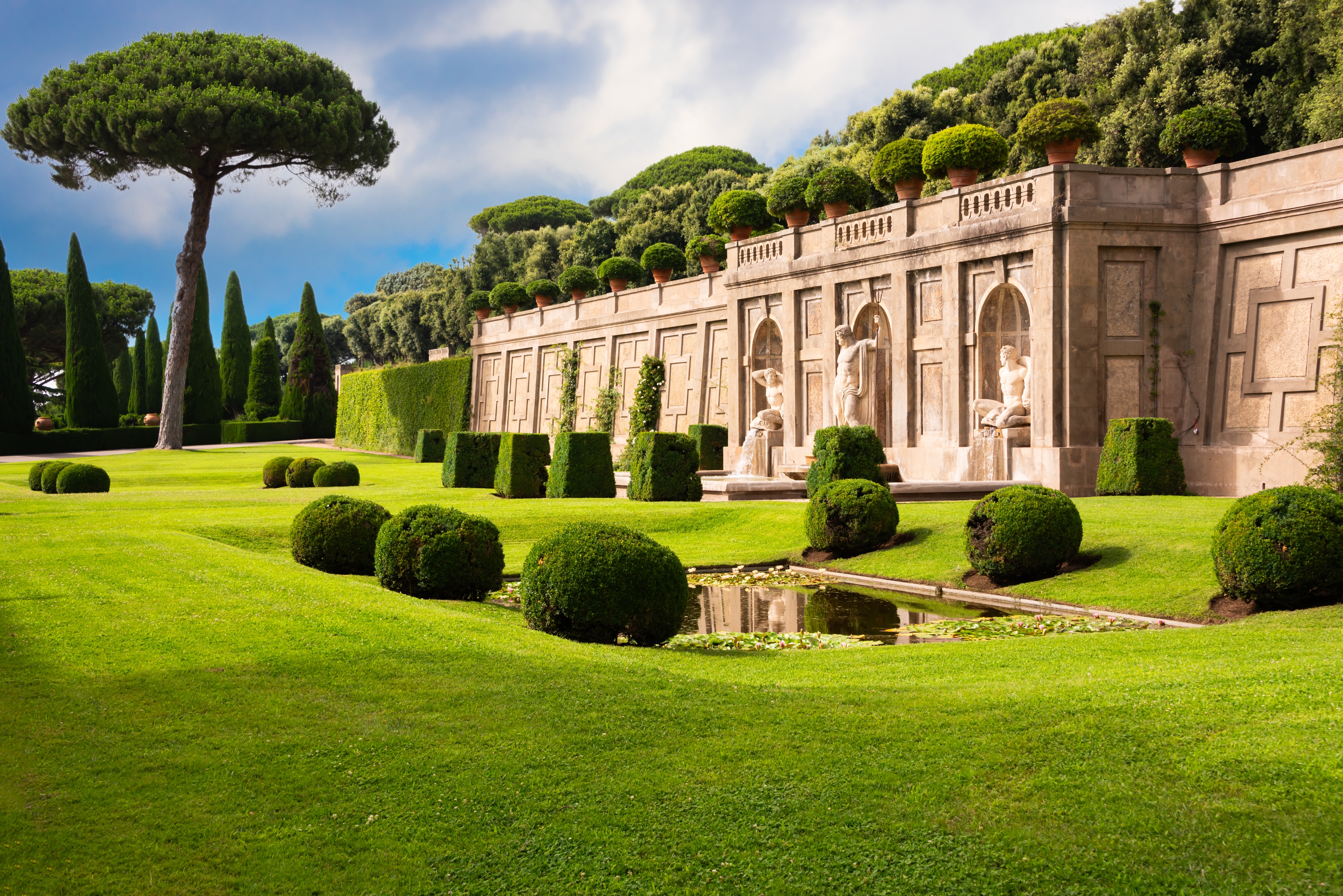 Storslåede pavelige haver ved Castel Gandolfo i Italien med velklippede hække, klassiske statuer og en dekorativ dam omgivet af cypresser og pinjetræer