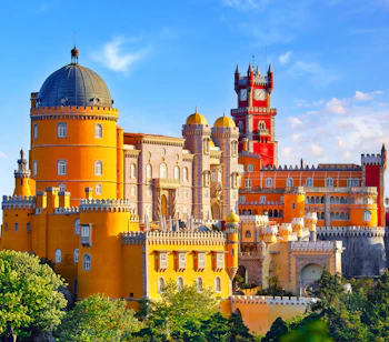 Farverigt Pena Palads med taarne og kupler i Sintra Portugal omgivet af groenne traeer