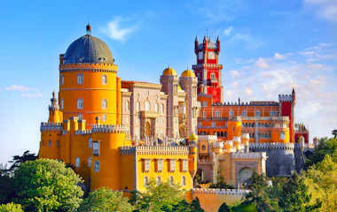 Farverigt Pena Palads med taarne og kupler i Sintra Portugal omgivet af groenne traeer
