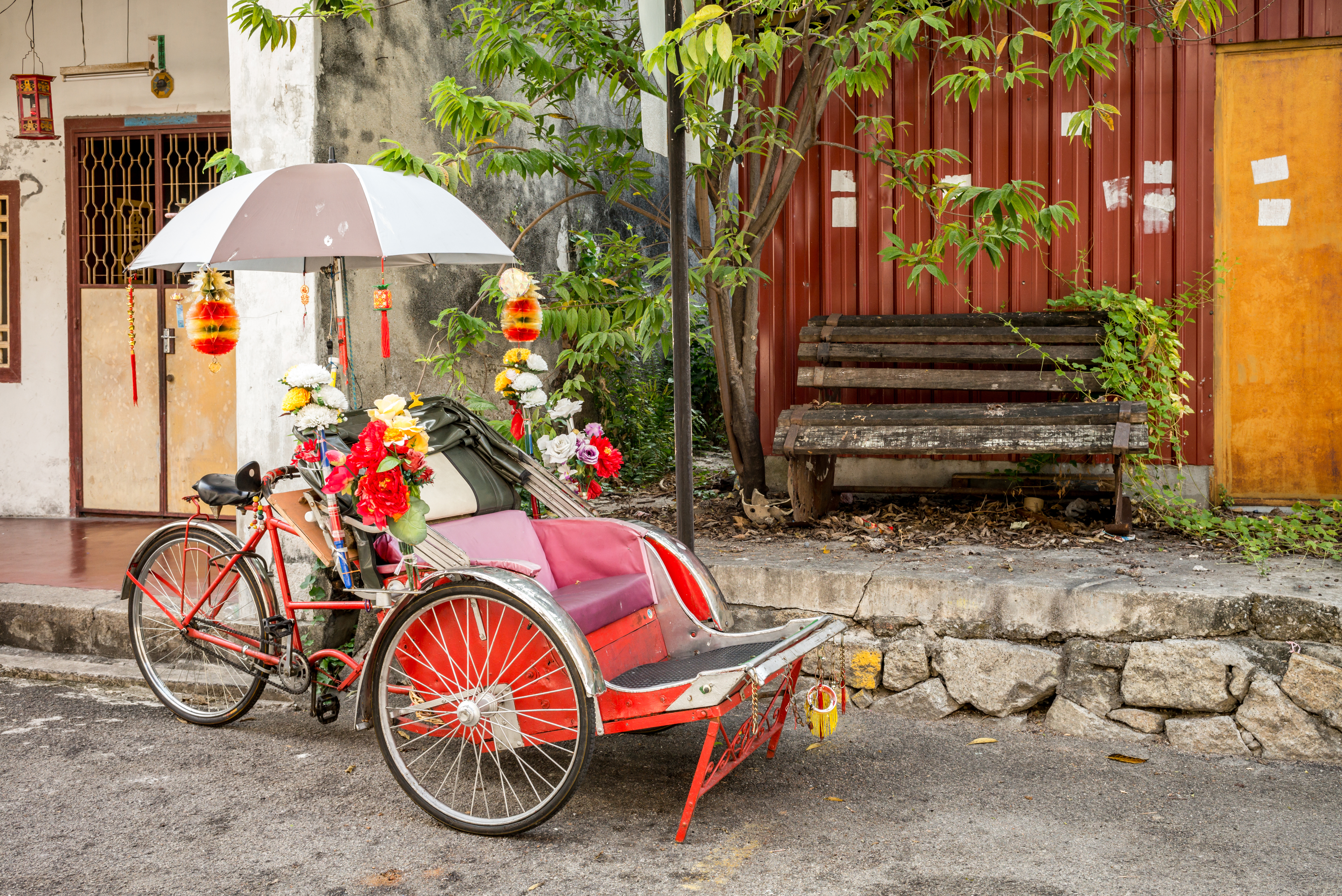 Traditionel trishaw parkeret ved en forfalden bygning i Penang, Malaysia - et autentisk glimt af lokal transportkultur og byens historiske charme